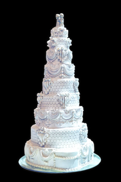 "Elegant multi-tiered wedding cake with white , royal icing adorned with intricate decorations—all parve and Pas Yisroel. Imperial Kosher